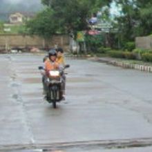 朝もやの中、早朝の街中を急ぐバイクタクシーと利用客の様子です