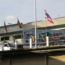 ミャンマー国旗とタイ国旗の間に、白色の街路灯の支柱が見えます