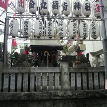 金丸稲荷神社の石柱の側壁と提灯です。壁越しに社が見えます。