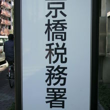 新富座跡の標識は、京橋税務署の標識の後方の緑地内にあります。