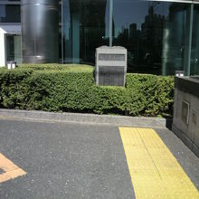 靴業発祥の地の石碑は、緑の植え込みの中に置かれています。