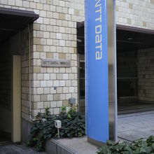 築地小劇場跡の標識が付けられた建物は、青い標柱の横にあります