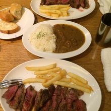 レアステーキとライスにカレーがかかってます