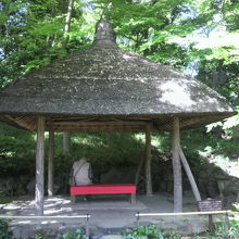 笠のような形の茅葺の屋根の丸屋の四阿です。赤い座席が鮮やか。