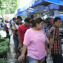 駐車場地区に開店している市場の魚貝類の露店の列とお客です。