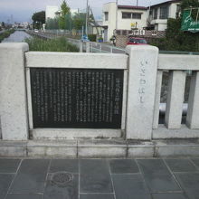 石和橋の欄干にある権三郎の石碑と背景の平等川の流れです。