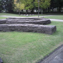 公園の緑の芝生の中に、石を積み上げた構造物が置かれています。