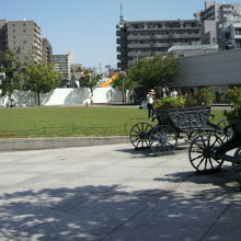アリオ川口の前の公園広場には、緑の芝生と馬車と建物が映えます