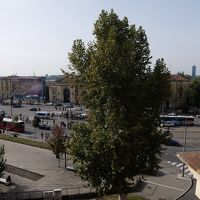 木の後ろの黄色い建物が駅、右奥の赤い建物がバスターミナル