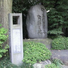 丸い講道館柔道発祥の地の石碑と解説の白い石碑が並んでいます。