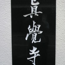 階段の中央にある黒いの標識です。黒地に白の文字で真覚寺の文字