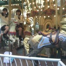 メリーゴーランドに乗って、写真撮影を楽しむ女子高校生です。