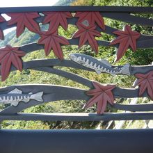 ダム堤上側面の山女魚と紅葉の飾り板