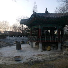 凍結した池の辺に建つ冬の鐘閣の様子