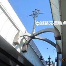 道路元標の上に浮かぶ「道路元標地点」の標識