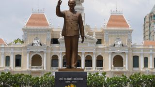人民委員会庁舎をバックに立つホーチミンさんの像です