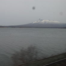 普通列車の車窓から眺める小沼湖越しの駒ヶ岳