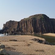 砂浜の目の前に立つ巨大な岩