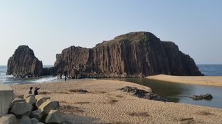 砂浜の目の前に立つ巨大な岩