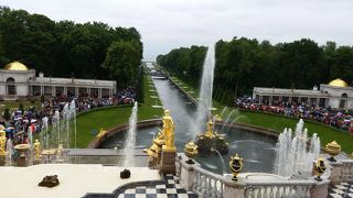 噴水と芝生や緑の木々、色とりどりの花が美しい