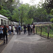 乗客がホームに降りて、滝を背景に記念写真を撮ったりしています