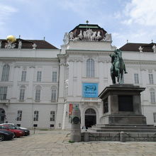 白いバロック建築の建物、入口はヨーゼフ２世像の後ろです