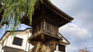 橋のたもとに柳の木と並んで建つ木製の燈籠