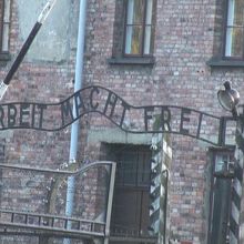 収容所の門に立つ「働けば自由になる」のプレートがむなしい