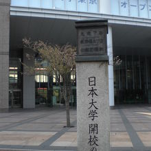 日本大学開校の地の石碑と目白通りの首都大学の建物の様子です。