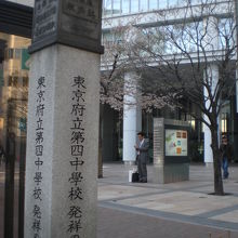 府立第４中学校発祥の石碑の背後には、東京区政会館が見えます。