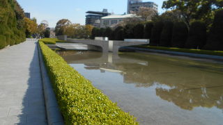 原爆死没者慰霊碑の三方を取り囲み　背後に長く伸びている池