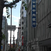 青い山梨中央銀行の標識が、白い建物の壁に対して、映えています