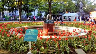 赤いチューリップに囲まれた「奉仕の道」の像