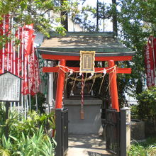 赤色の幟に囲まれた草分稲荷神社です。左側に解説板があります。