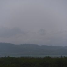 手前の森と奥の山の間に薄っすらと湖が見えます