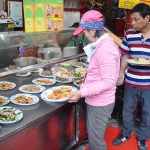 出来上がっている料理の皿を選んで近くの店のテーブルにすわる