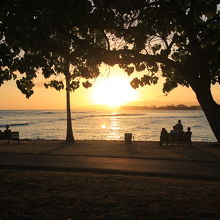 ベンチで夕日を見ながらハワイを楽しむ人