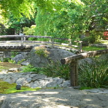 梅園の中の筆塚の前の様子と傍にある古橋の取り合わせの写真です