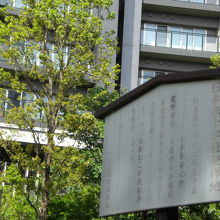 逓信病院の建物を背景とする日本赤十字社発祥の地の標識です。