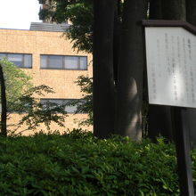 逓信病院の建物を背景とする日本赤十字社発祥の地の標識です。