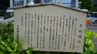 歩道の植え込みの中に木製の説明板