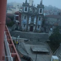 部屋の窓から見た朝もやの中のサント・イルデフォンソ教会