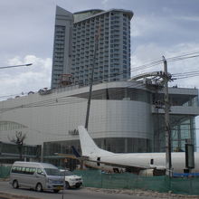 高層の建物と手前の広大な建物、大型ジェット機が小さく見えます