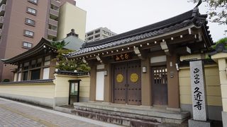 いかめしい山門と塀の後ろに方形屋根の本堂