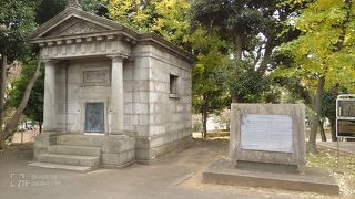 重々しい水準原点標庫と新しい電子基準点が並ぶ風景