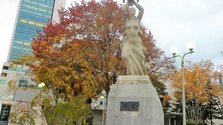 白い女性像で足が前を歩んで両手で鳩を持って