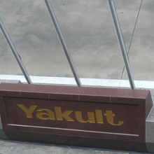 青色に眩しいビルの地上入口の前には、ヤクルトの文字が見えます
