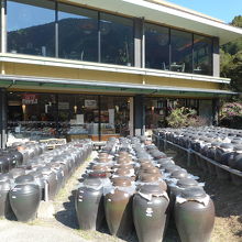 店外の黒酢醸造中の甕と店舗