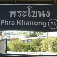 ＢＴＳブラカノン駅の標識です。背景に、緑の樹々が見えます。