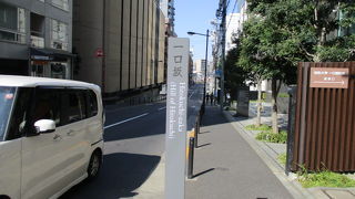 ビルや店舗が立ち並ぶ都会の舗装されたなだらかな坂です。　